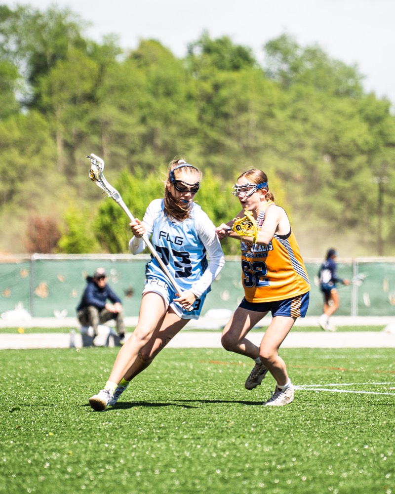 An FLG attacker in Carolina blue driving past a defender.
