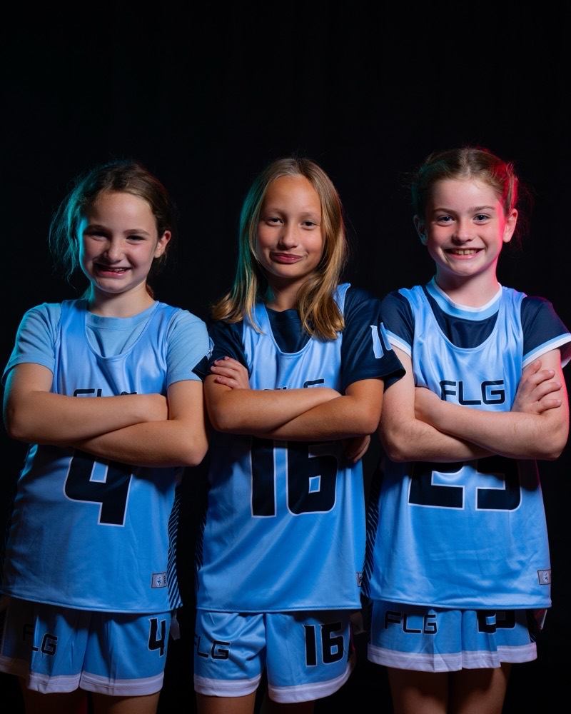 Three FLG youth players in Carolina blue, arms folded.